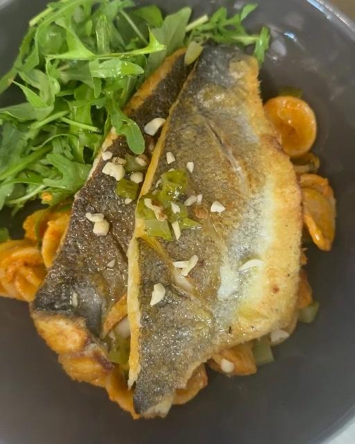 Pan-fried sea bass fillets with crisp skin, pasta and rocket
